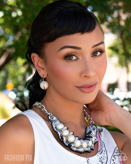 Woman wearing a pearl necklace with a blurred outdoor background