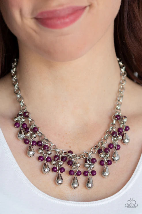 Necklace with purple beads and silver accents worn by a person