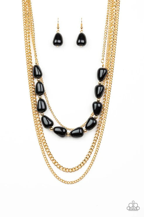 Gold necklace with black beads and matching earrings on a white background