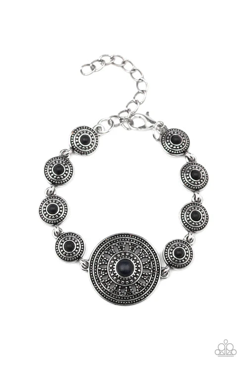 Silver bracelet with black circular stones on a white background