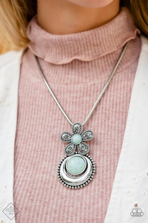 Necklace with a decorative pendant worn by a person in a pink sweater.