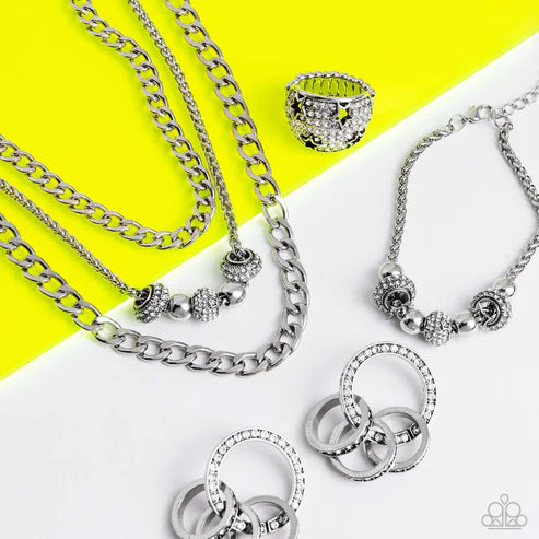Silver jewelry including necklaces and rings on a yellow and white background