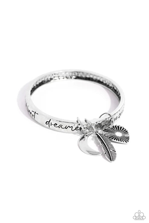 Silver ring with feather charm and 'just dreamer' text on a white background