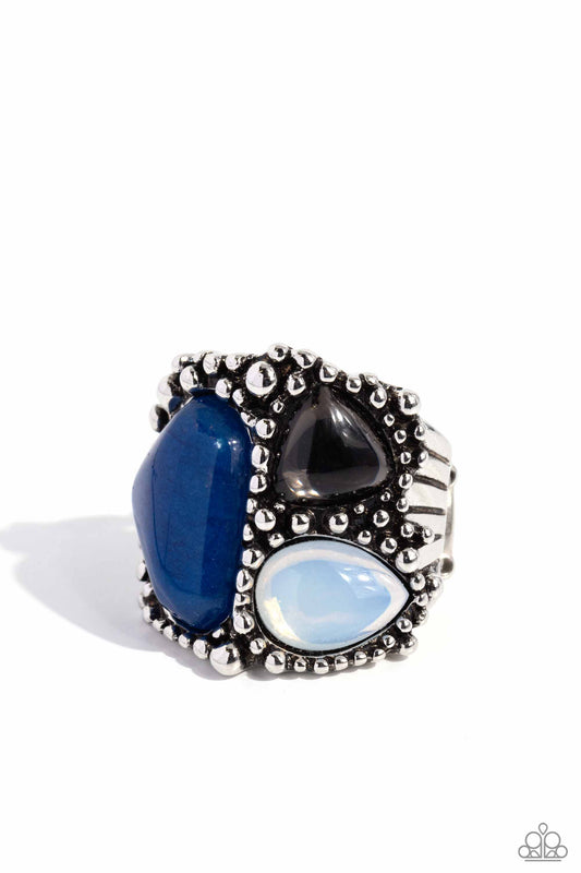 Silver ring with blue, black, and white gemstones on a white background