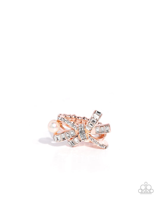 Rose gold bow-shaped ring with gemstones on a white background