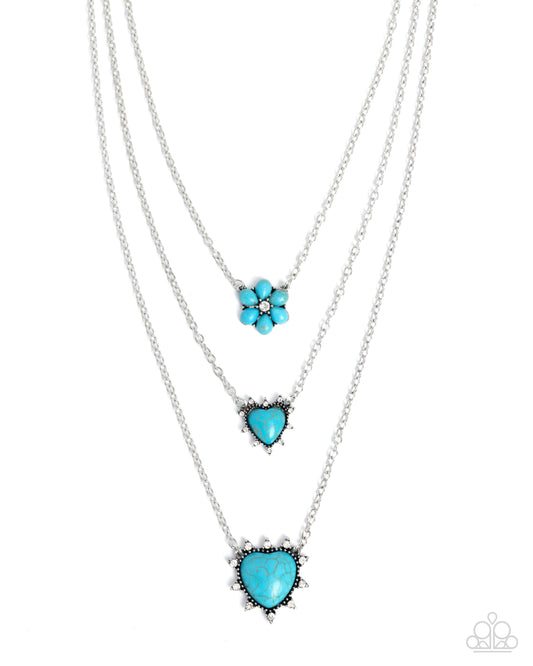 Three layered silver necklaces with turquoise blue pendants, including a flower, heart, and larger heart design, displayed on a clean white background.