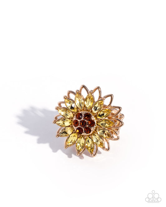 Gold and yellow flower-shaped brooch on a white background