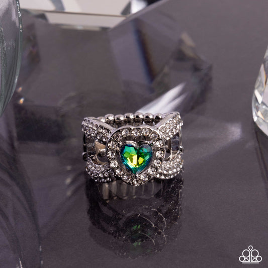 Silver ring with a green gemstone on a reflective surface