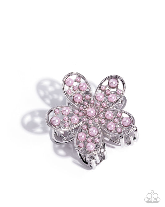 Pink flower-shaped hair clip with silver accents on a white background