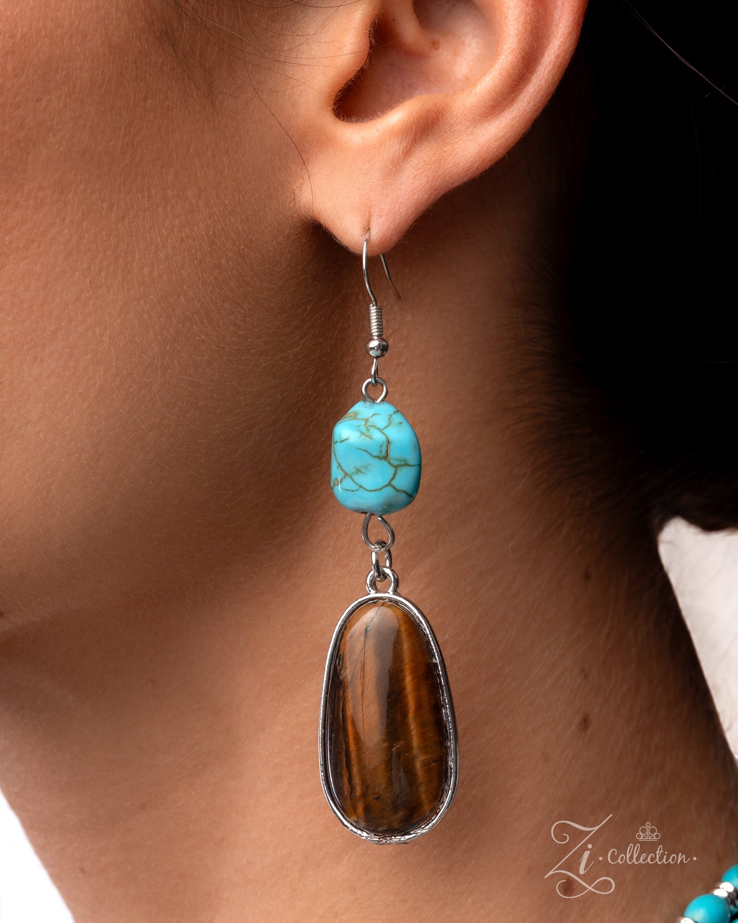 Earring with turquoise bead and brown stone on a blurred background