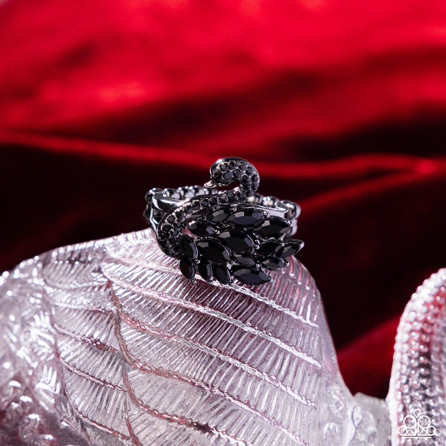 Black ring on a textured white surface with a red fabric background
