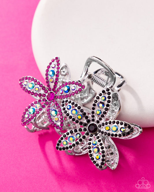 Decorative keychains with floral designs and colorful gemstones on a pink background