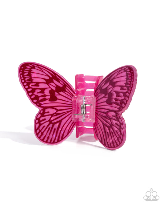 A bright pink butterfly-shaped hair claw clip with dark magenta wing patterns, shown on a clean white background.