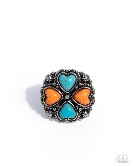 Silver ring with turquoise and orange heart-shaped stones on a white background