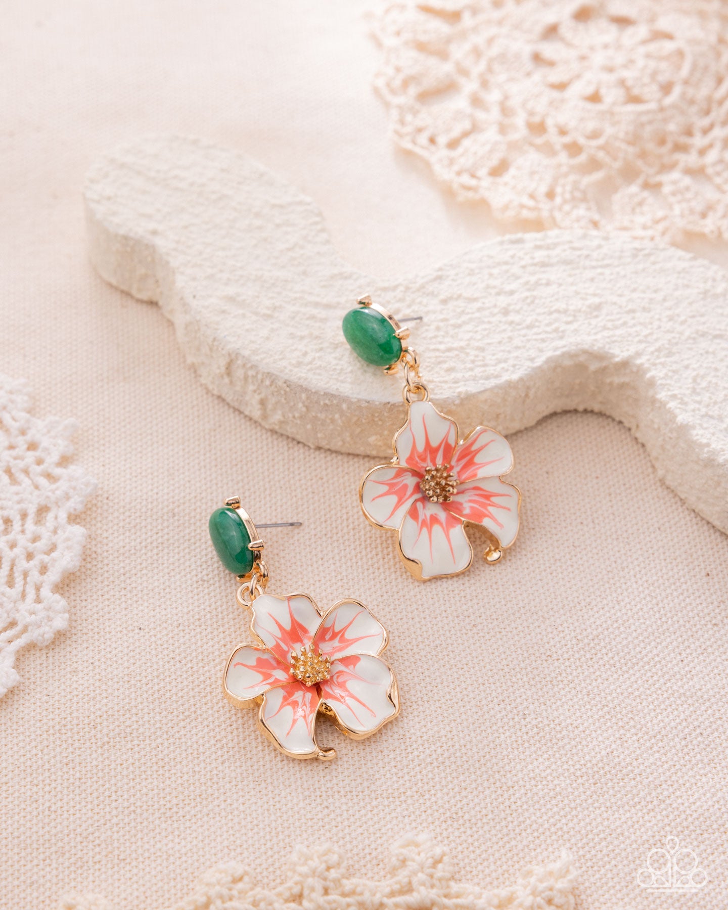 Floral earrings with green beads on a textured surface