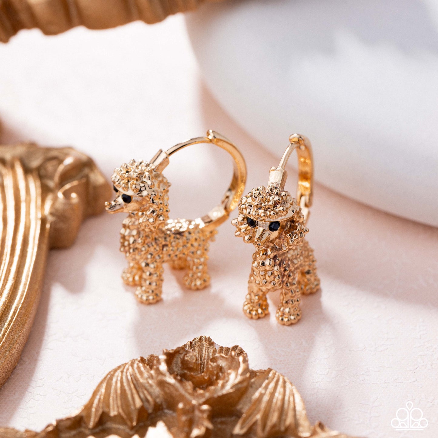 Gold dog-shaped earrings on a white background