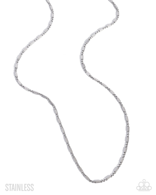 A stainless steel link chain necklace with elongated oval links, displayed in a curved S-shape on a white background with 'STAINLESS' text in the bottom-left corner.