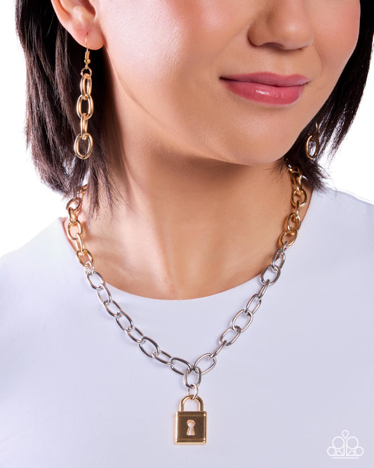 A close-up of a woman wearing a silver chain necklace with a gold padlock pendant and matching gold drop earrings against a white background.