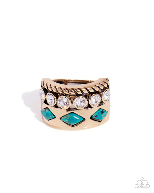 A gold-toned wide band ring featuring a twisted rope texture, clear round crystals, and turquoise-colored diamond-shaped stones, shown on a white background.