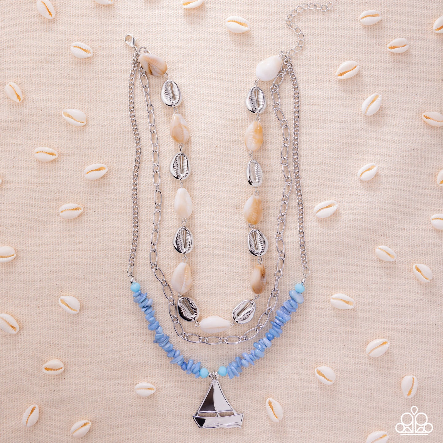 Necklace with shell and blue bead accents on a beige background with cowrie shells.