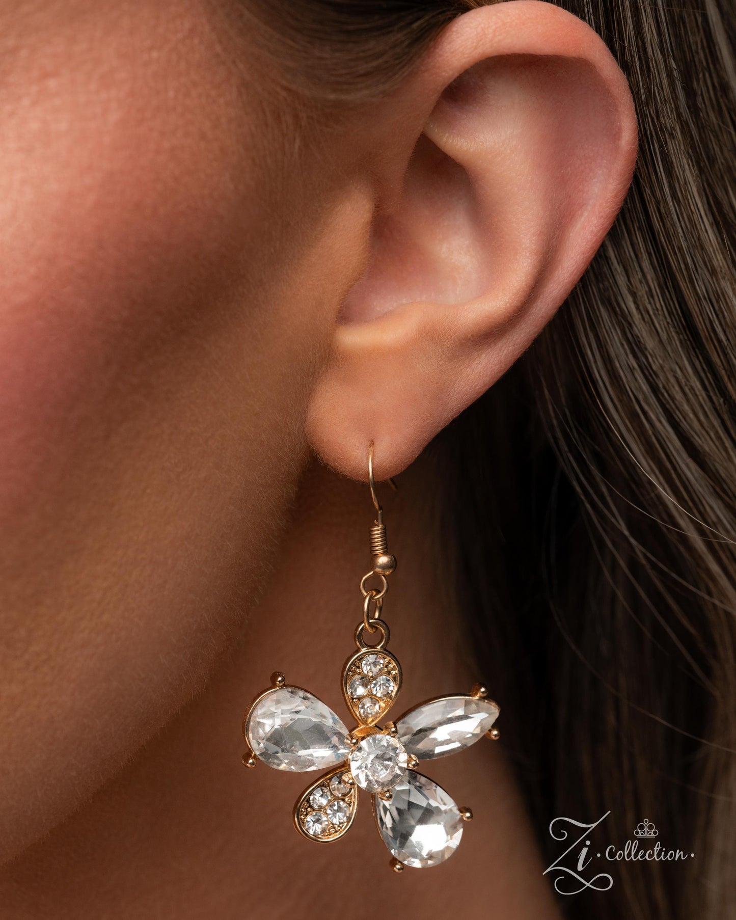 Close-up of a woman's ear wearing a decorative earring with a visible brand logo.