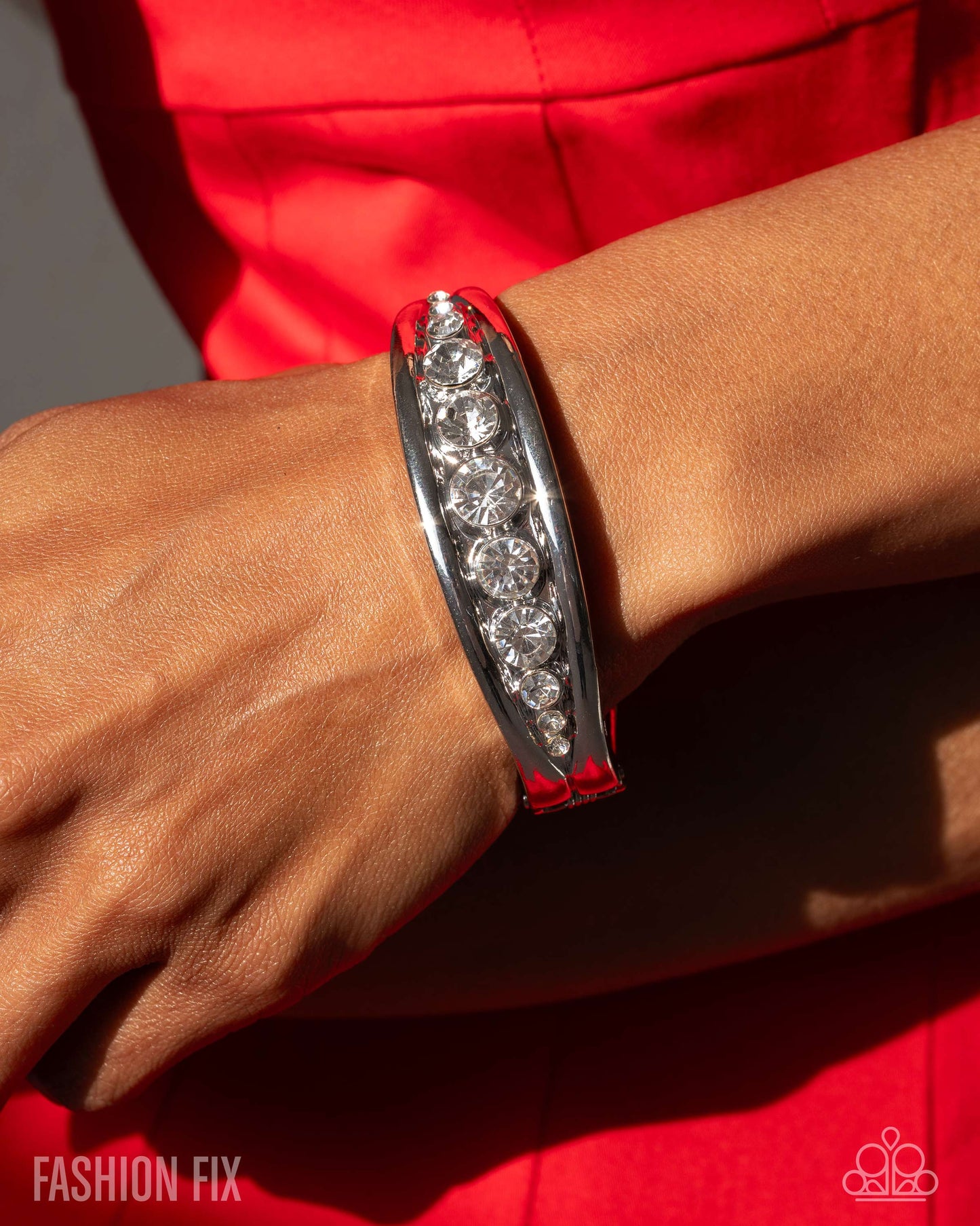 Silver bracelet with red accents on a wrist against a red background