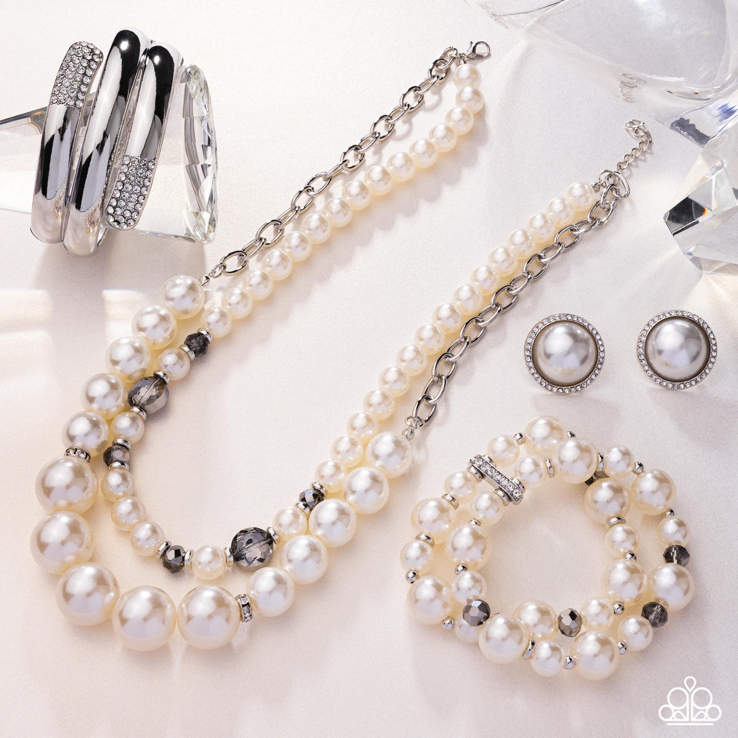 Pearl jewelry set including necklace, earrings, and bracelet on a white surface.