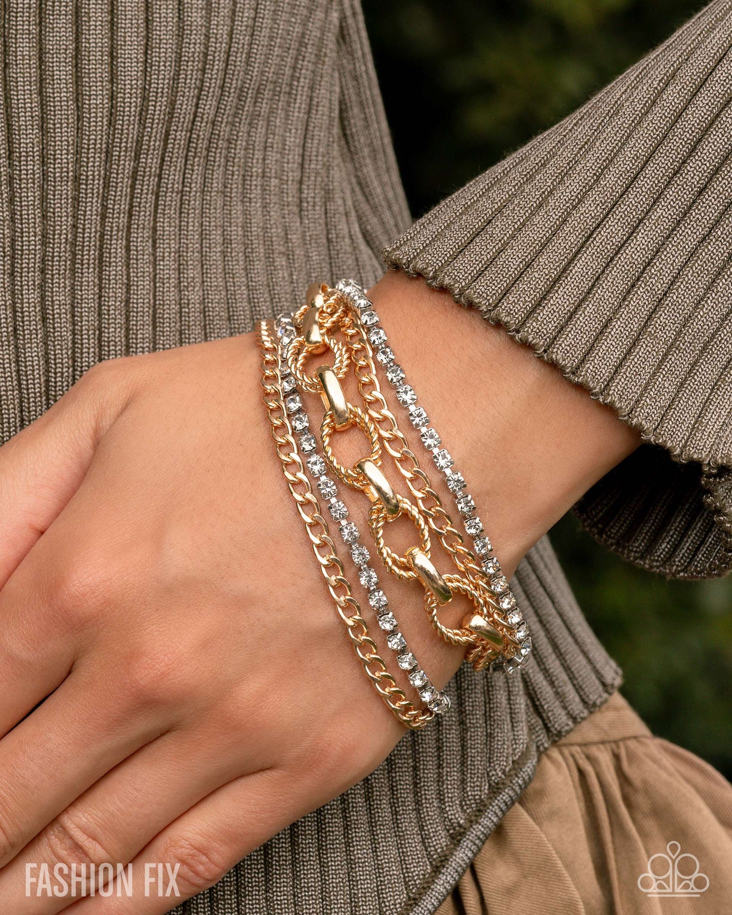 Gold and silver chain bracelets on a wrist with a blurred background