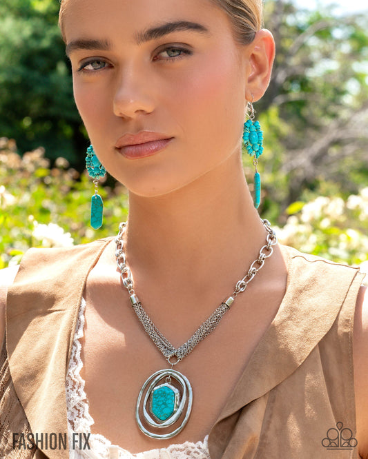 Woman wearing turquoise earrings and a necklace with a large pendant outdoors