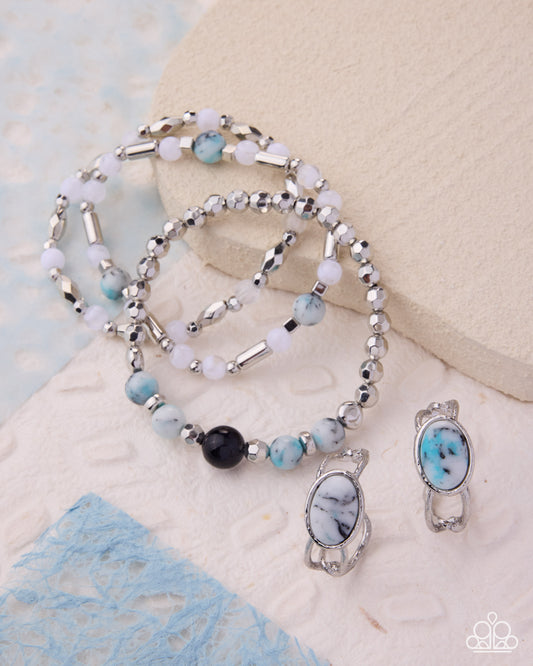 Beaded necklace and earrings with turquoise and black stones on a textured surface