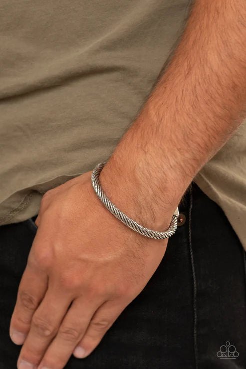 Silver bracelet on a wrist with a neutral background