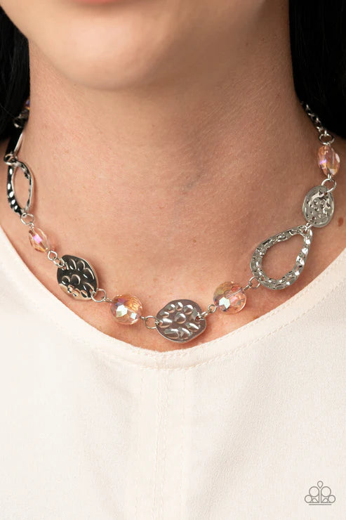 Hammered silver frames and imperfect silver ovals link with iridescent pink gems below the collar, creating a colorful display. Features an adjustable clasp closure.

Sold as one individual necklace. Includes one pair of matching earrings.