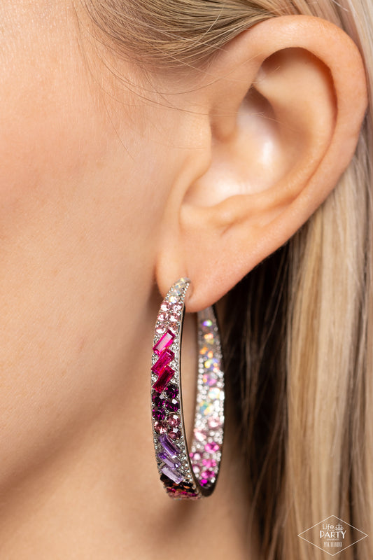 Close-up of an ear wearing a colorful hoop earring with a blurred background
