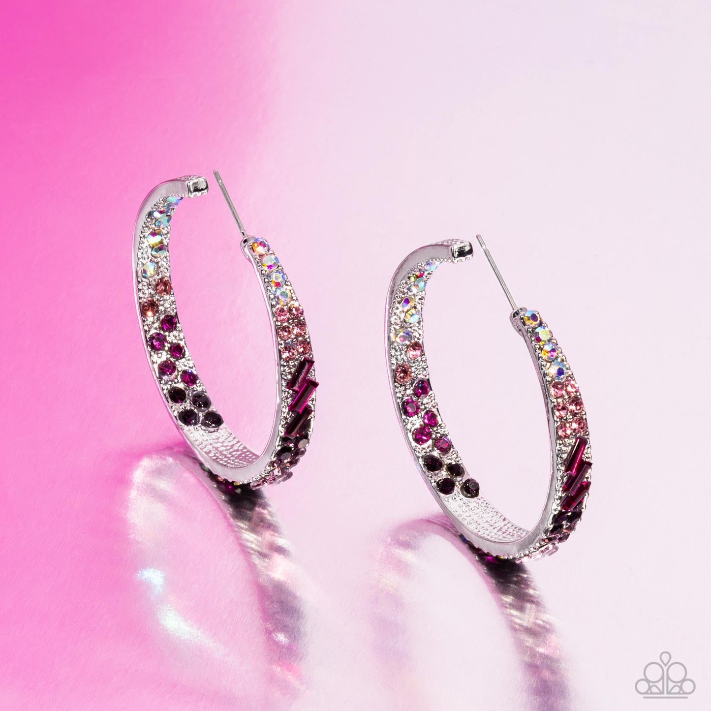 Silver hoop earrings with multicolored gemstones on a pink background