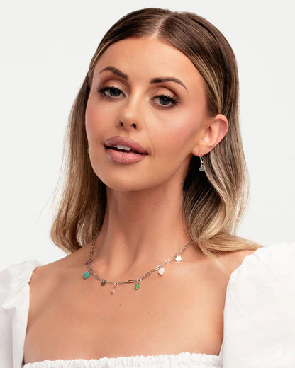 Woman wearing a delicate necklace with small stones on a plain background