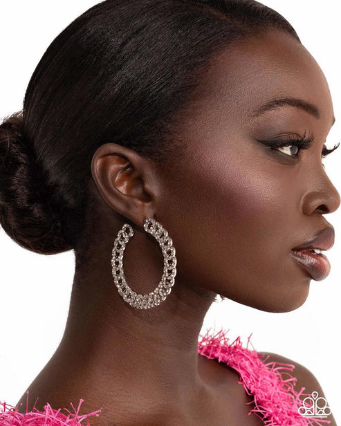 Woman wearing large hoop earrings with a pink textured garment on a white background