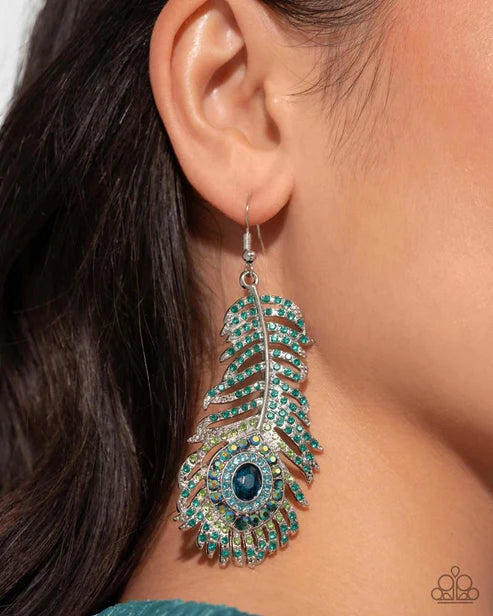 Close-up of a person wearing a decorative earring with green and blue stones.