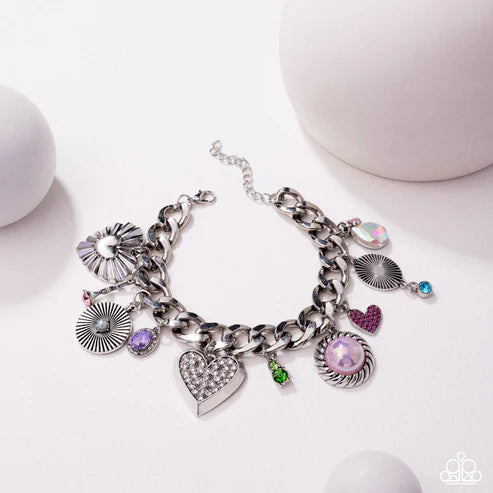 Silver charm bracelet with various charms on a white background