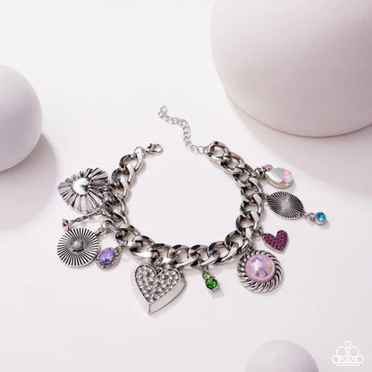 Silver charm bracelet with various charms on a white background