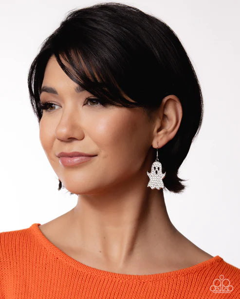 Woman wearing a silver hamsa hand earring against a white background