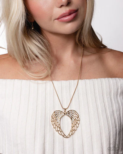 Woman wearing a gold necklace with an angel wing pendant on a white background