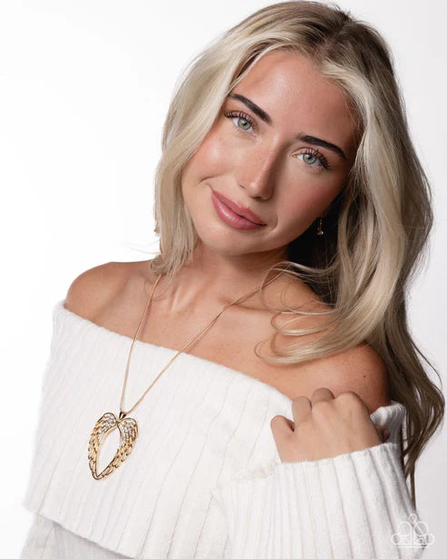 Woman wearing a white off-shoulder top and a gold necklace with a heart pendant on a white background