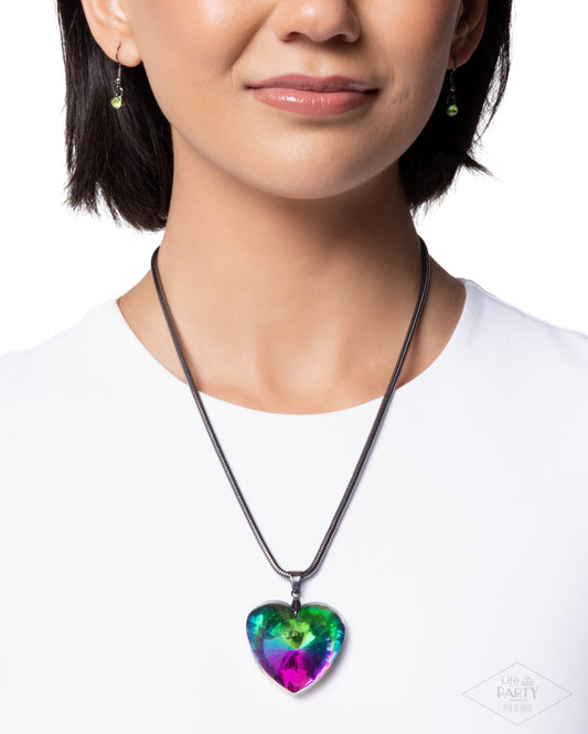 Person wearing a necklace with a colorful heart-shaped pendant on a white background