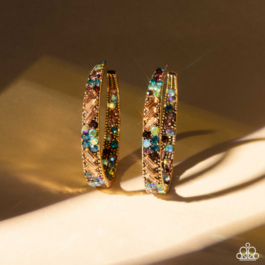 Gold hoop earrings with multicolored gemstones on a beige surface with soft shadows.