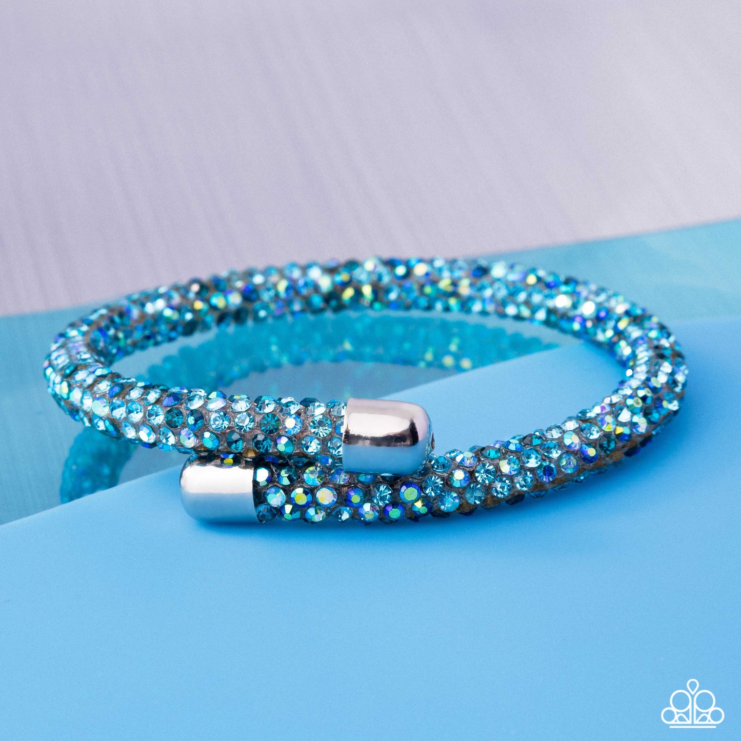 Blue beaded bracelet with silver clasp on a blue surface