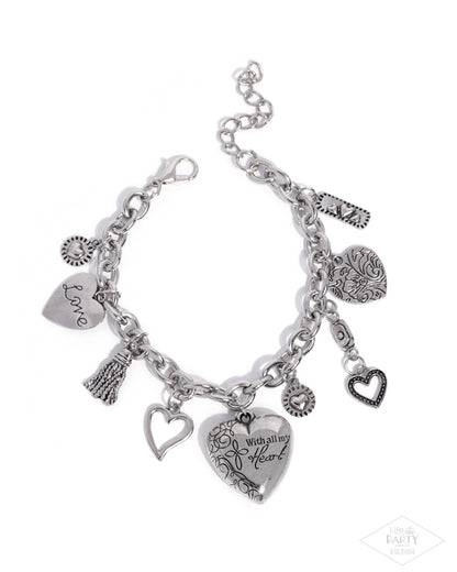 Silver charm bracelet with various charms on a white background