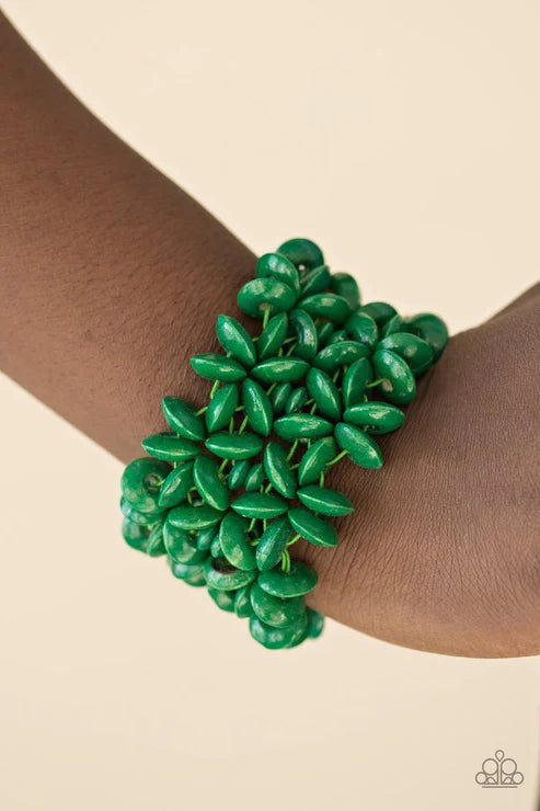 Green leaf-patterned bracelet on a wrist against a beige background