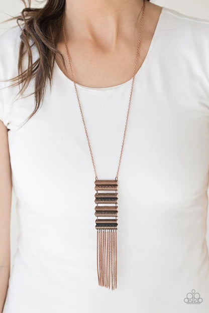 Long, layered necklace worn by a person on a white background