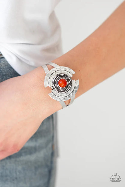 Silver bracelet with a red stone on a wrist against a white background