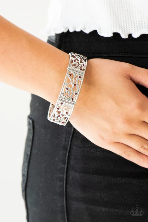 Silver bracelet with intricate design worn on wrist against a neutral background